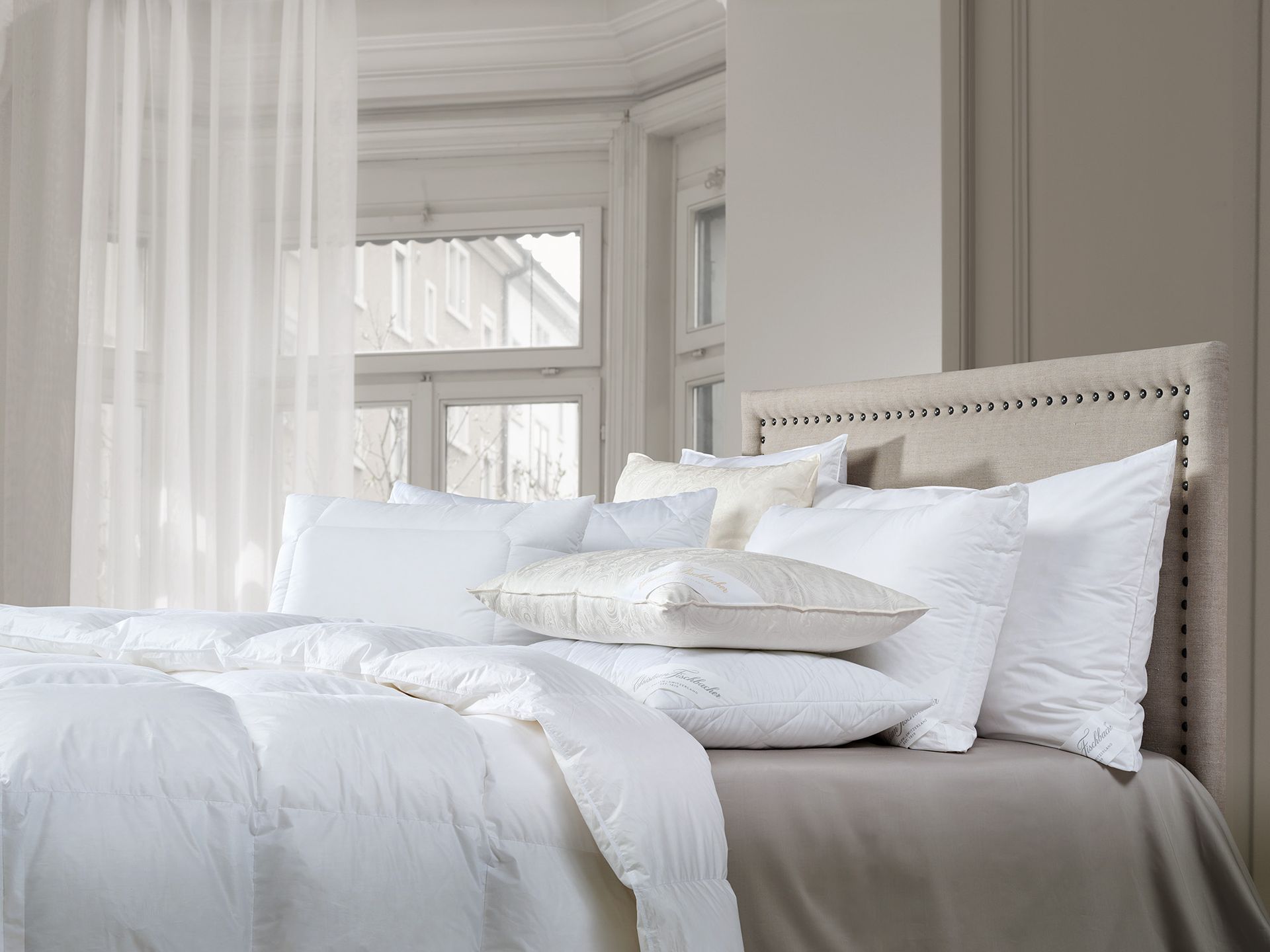 A bed with white sheets and pillows in a bedroom.