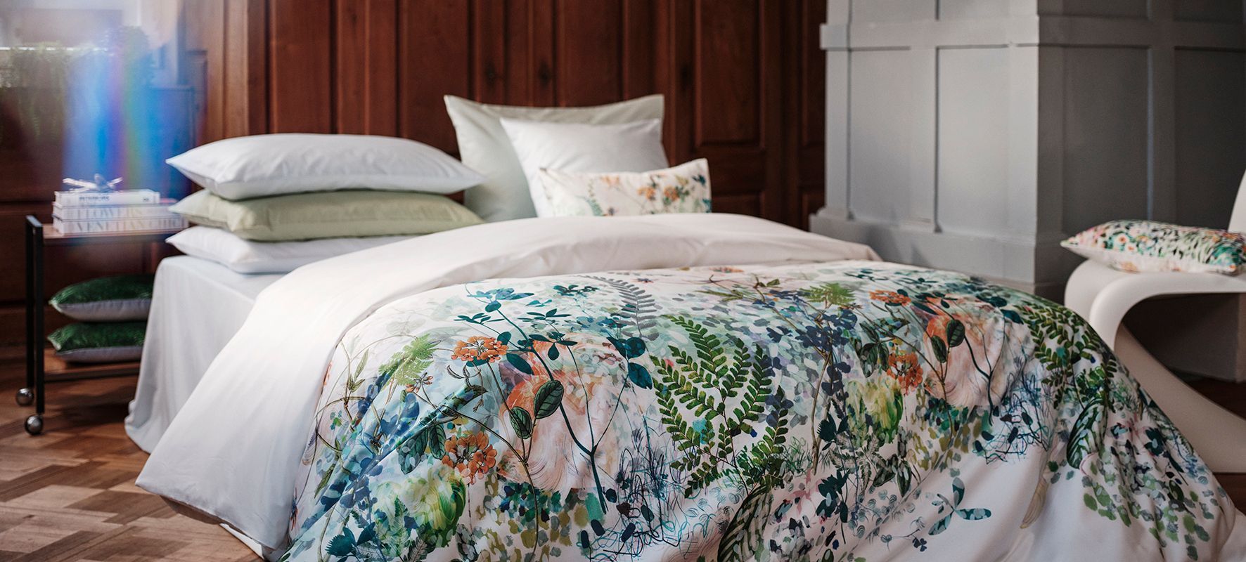A bed with a floral comforter and pillows in a bedroom.
