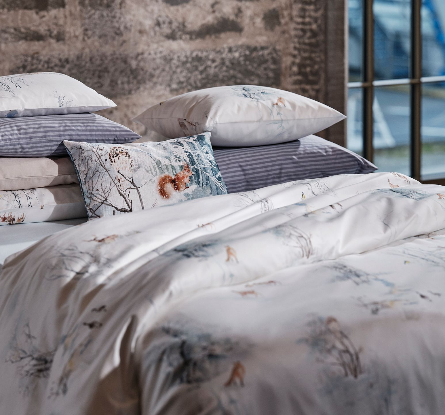Bed with white and blue floral bedding and several pillows.