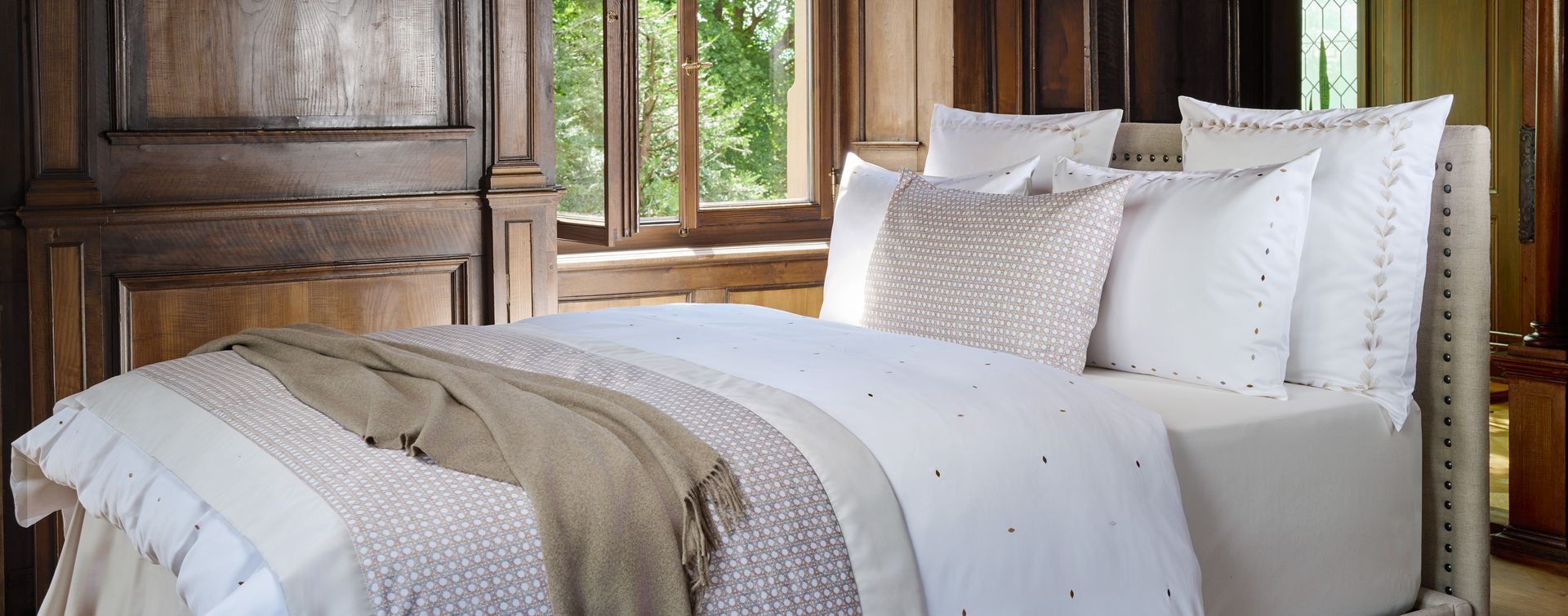 A bed with white sheets and pillows in a bedroom with a window.