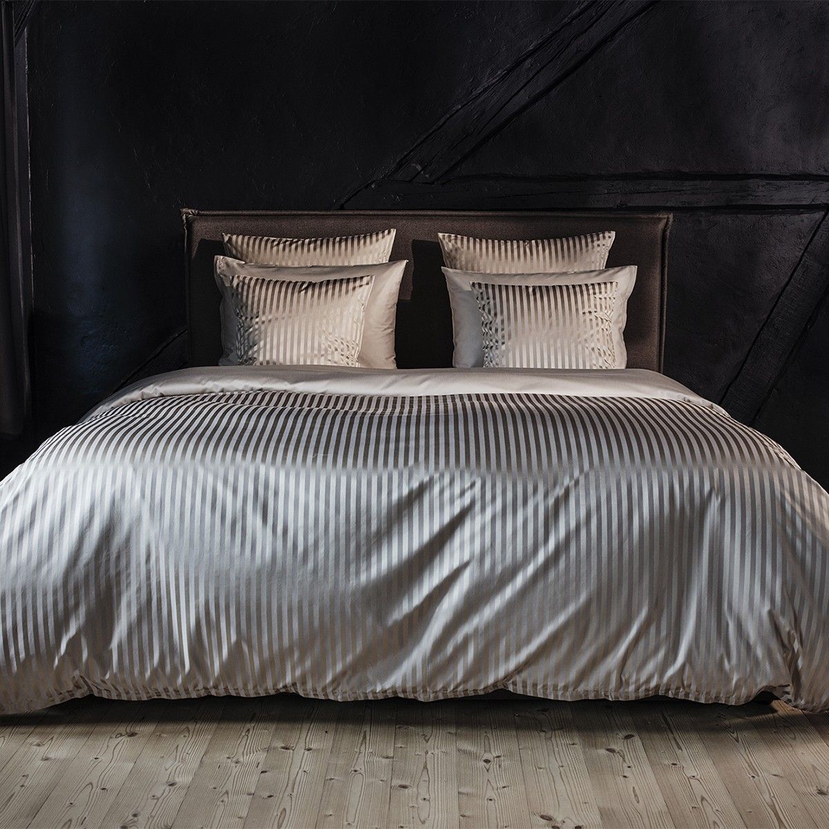 White bed with ribbed duvet and pillows, dark background.