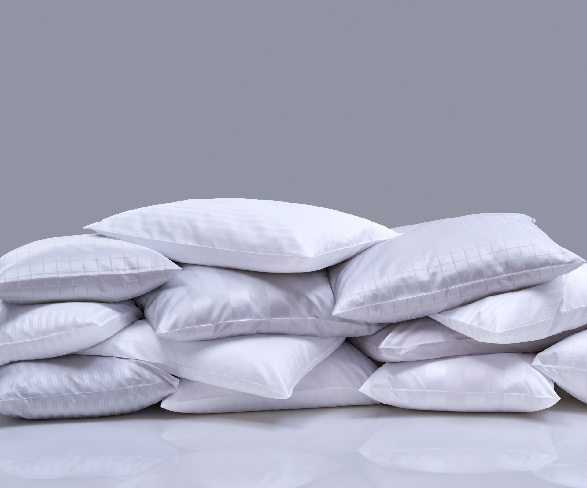 Pile of white pillows stacked against a gray background.