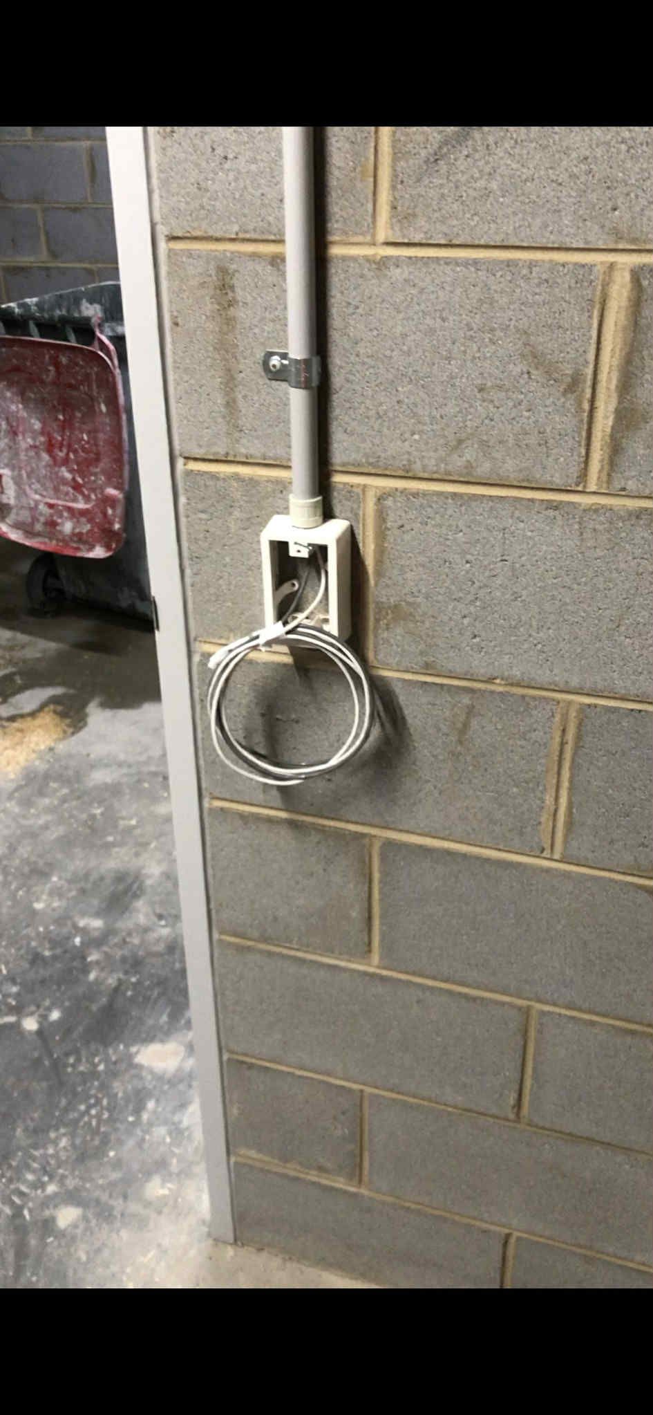 Weatherproof outdoor power outlet installed on a rendered brick wall