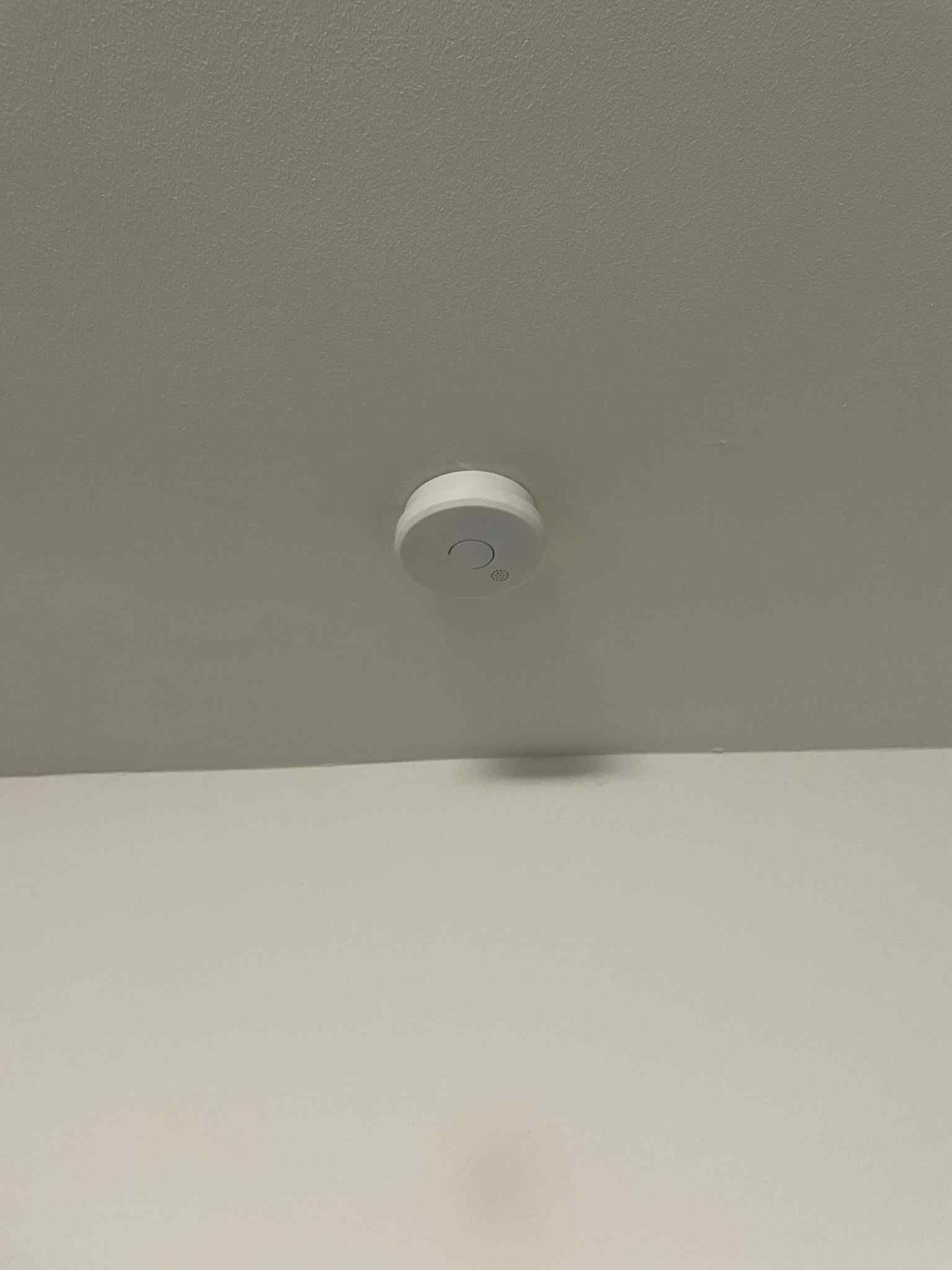 Close-up of modern photoelectric smoke detector on ceiling