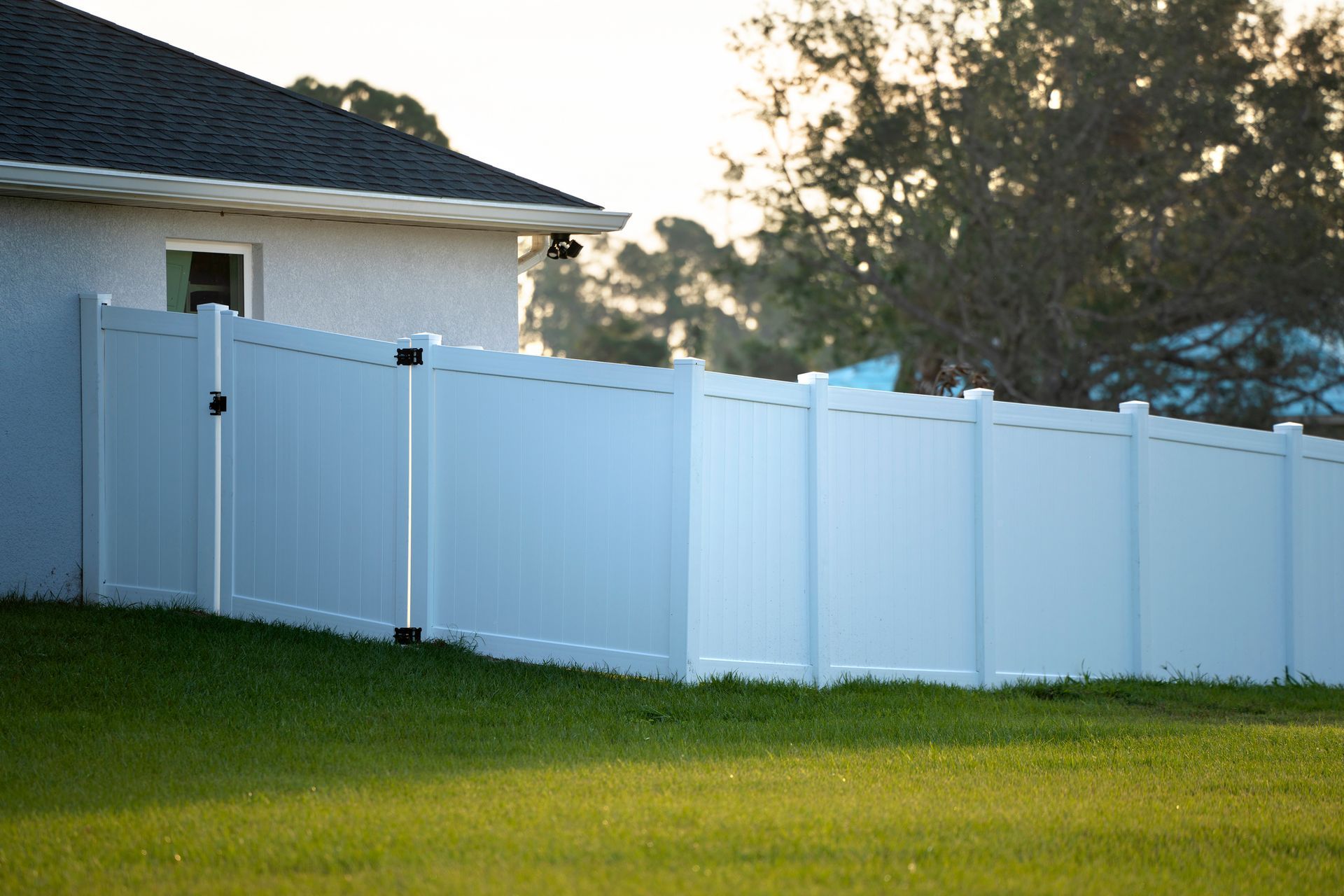 White vinyl fence surrounding a house on a grassy hill. White vinyl fence surrounding a house on a grassy hill.