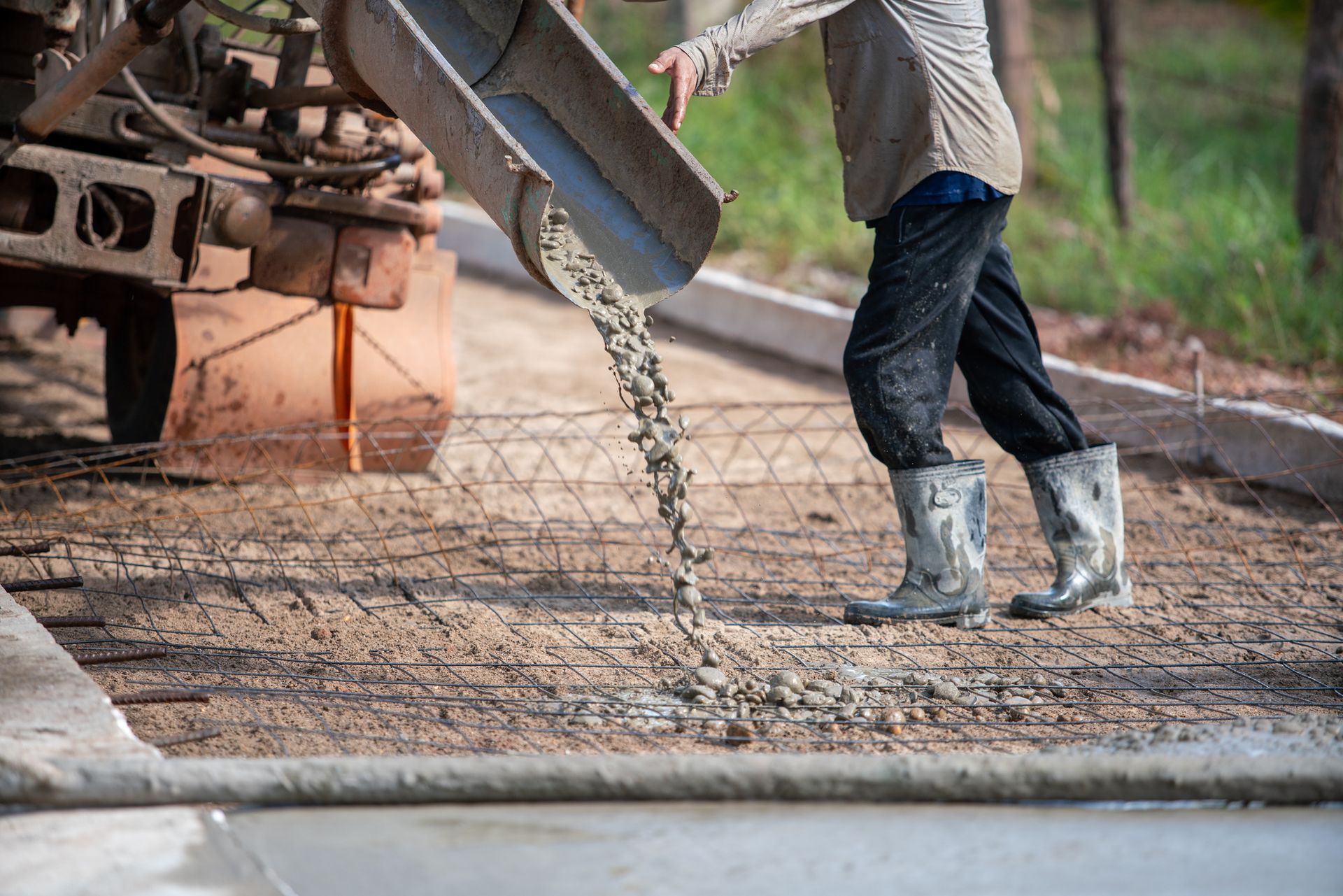Construction worker pouring concrete from a truck onto a rebar grid at a construction site.