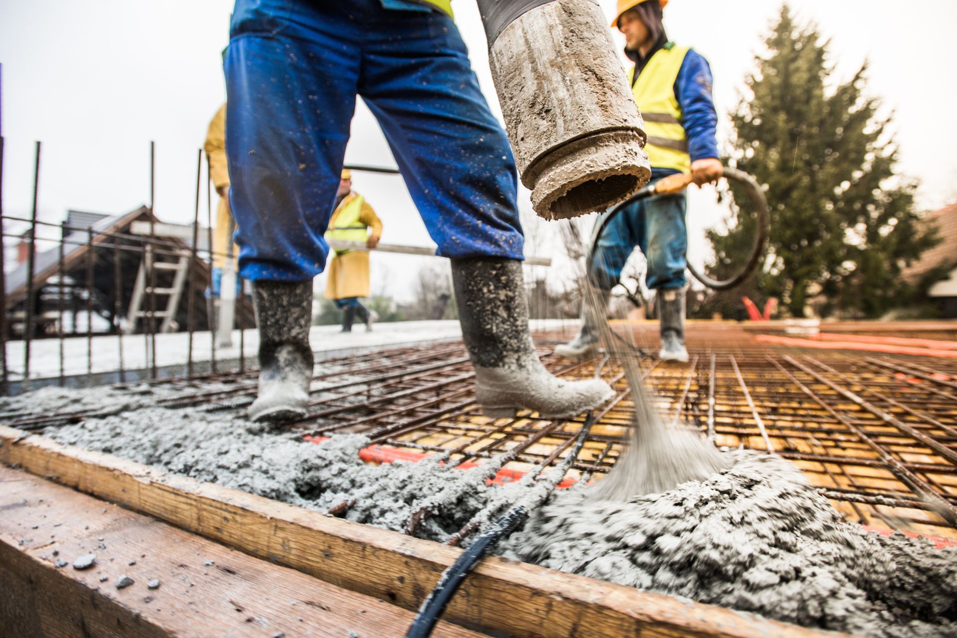 Construction workers pouring concrete onto rebar, wearing safety gear, outdoors. Construction workers pouring concrete onto rebar, wearing safety gear, outdoors.