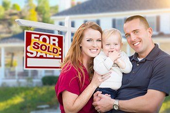 Family in Front of Sold Sign and House — Trust Litigation Attorneys in Austin, MN