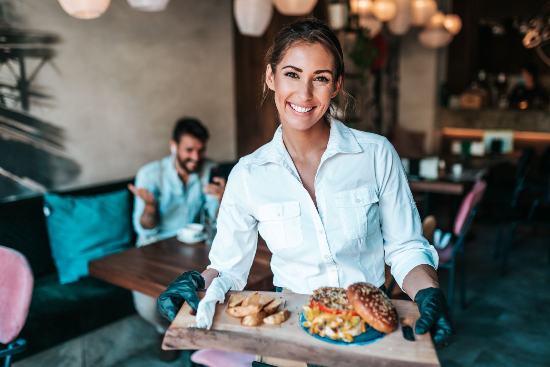 A waitress is holding a tray of food in a restaurant.