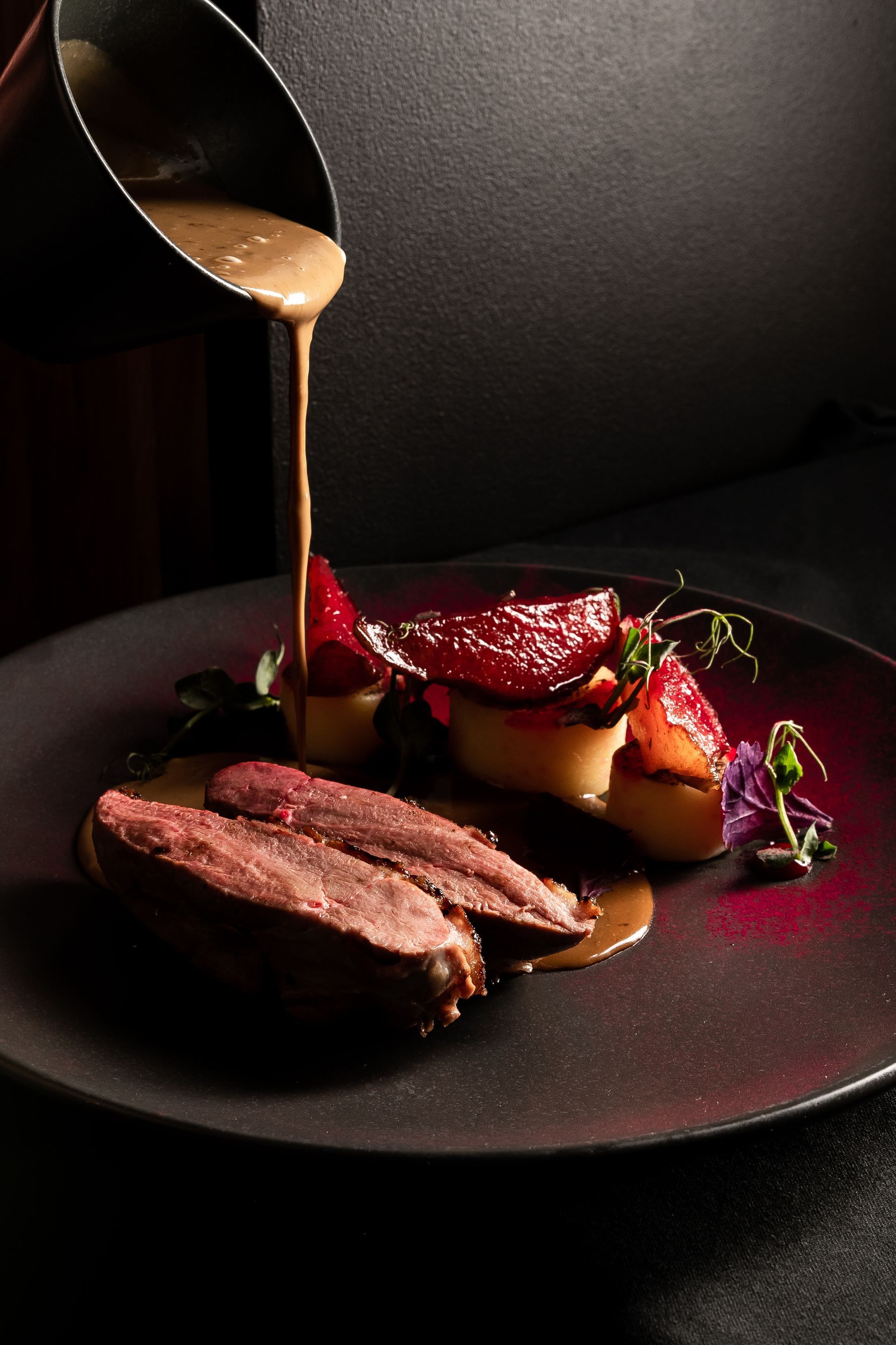 A close up of a plate of food with sauce being poured on it.