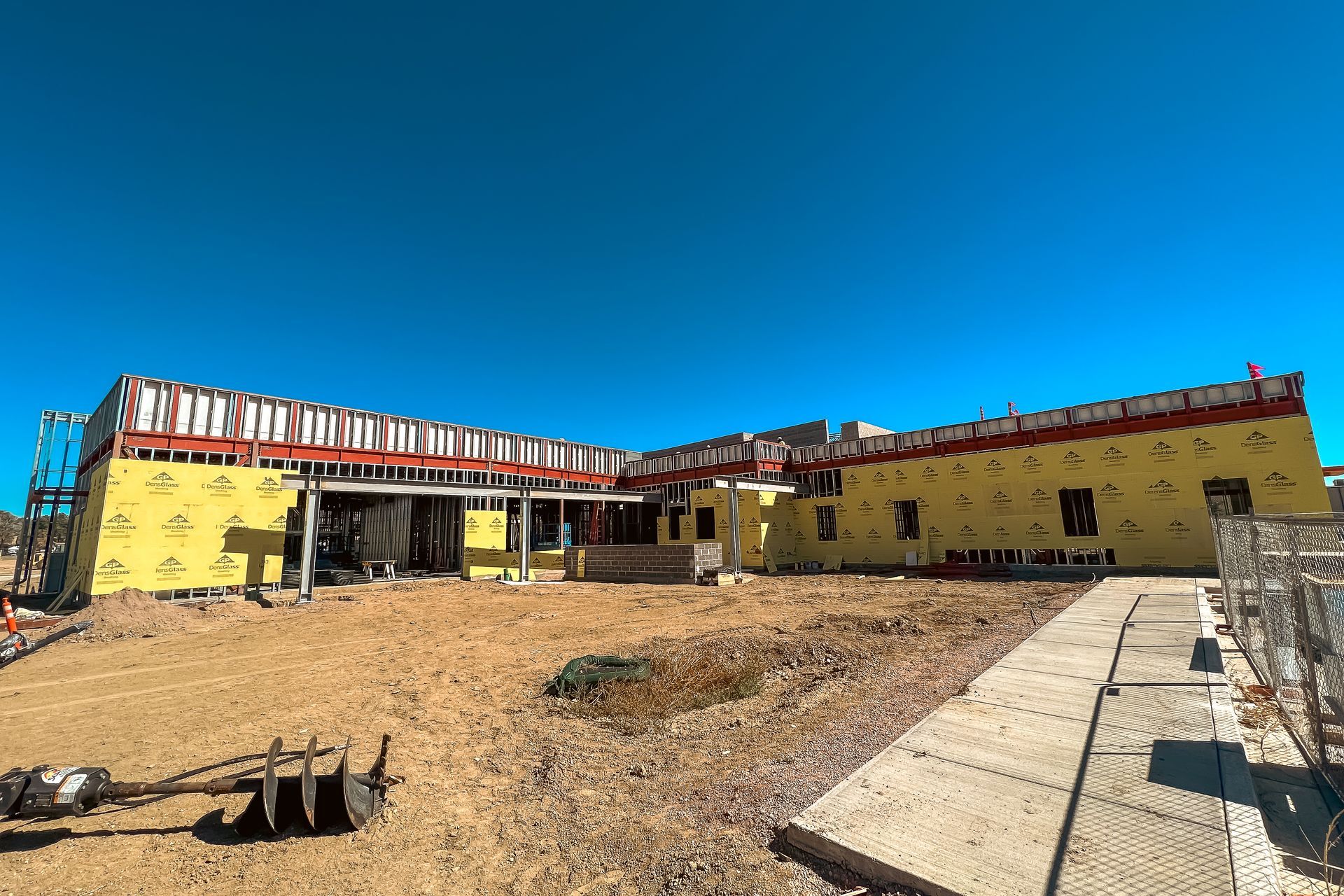 A large yellow building is being built in a dirt field.