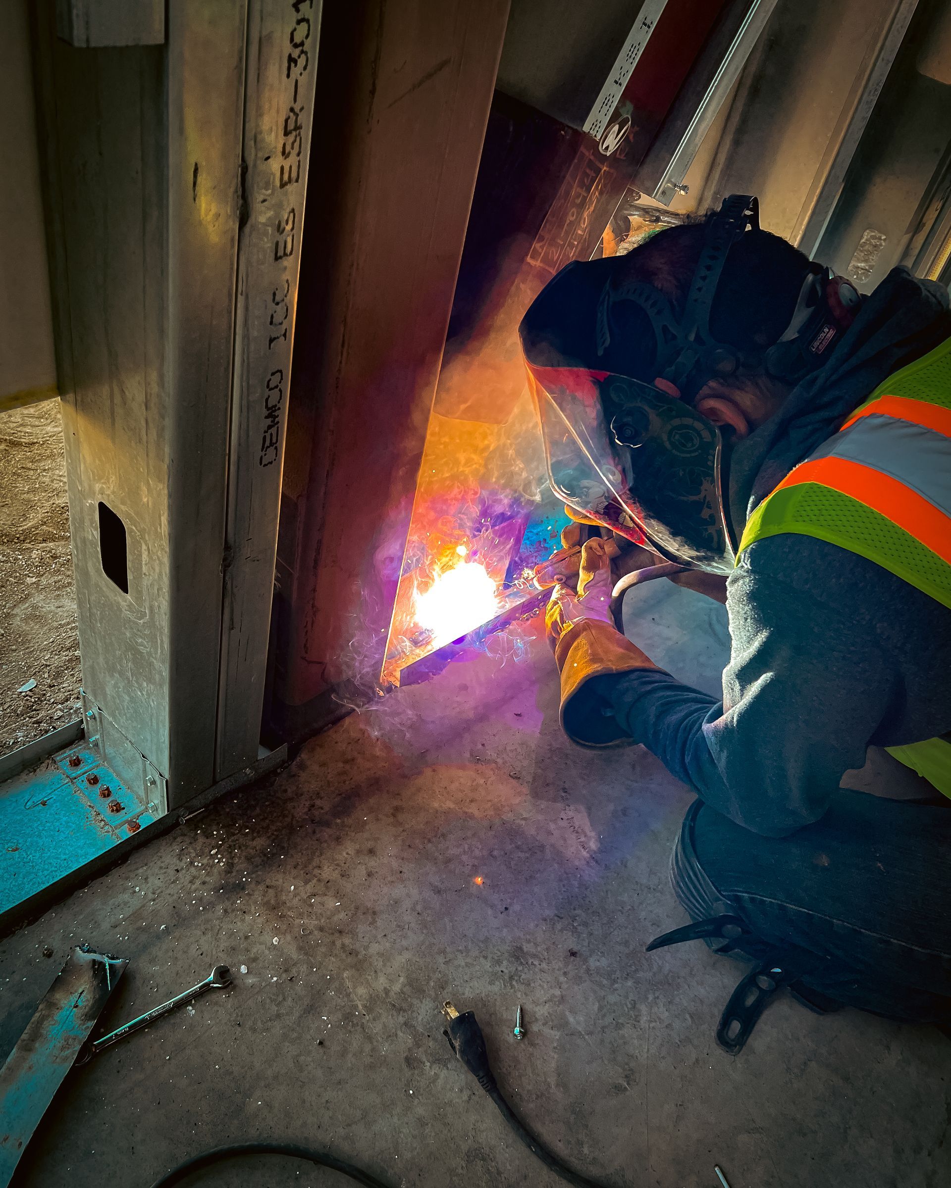 A man wearing a welding mask is welding a piece of metal.