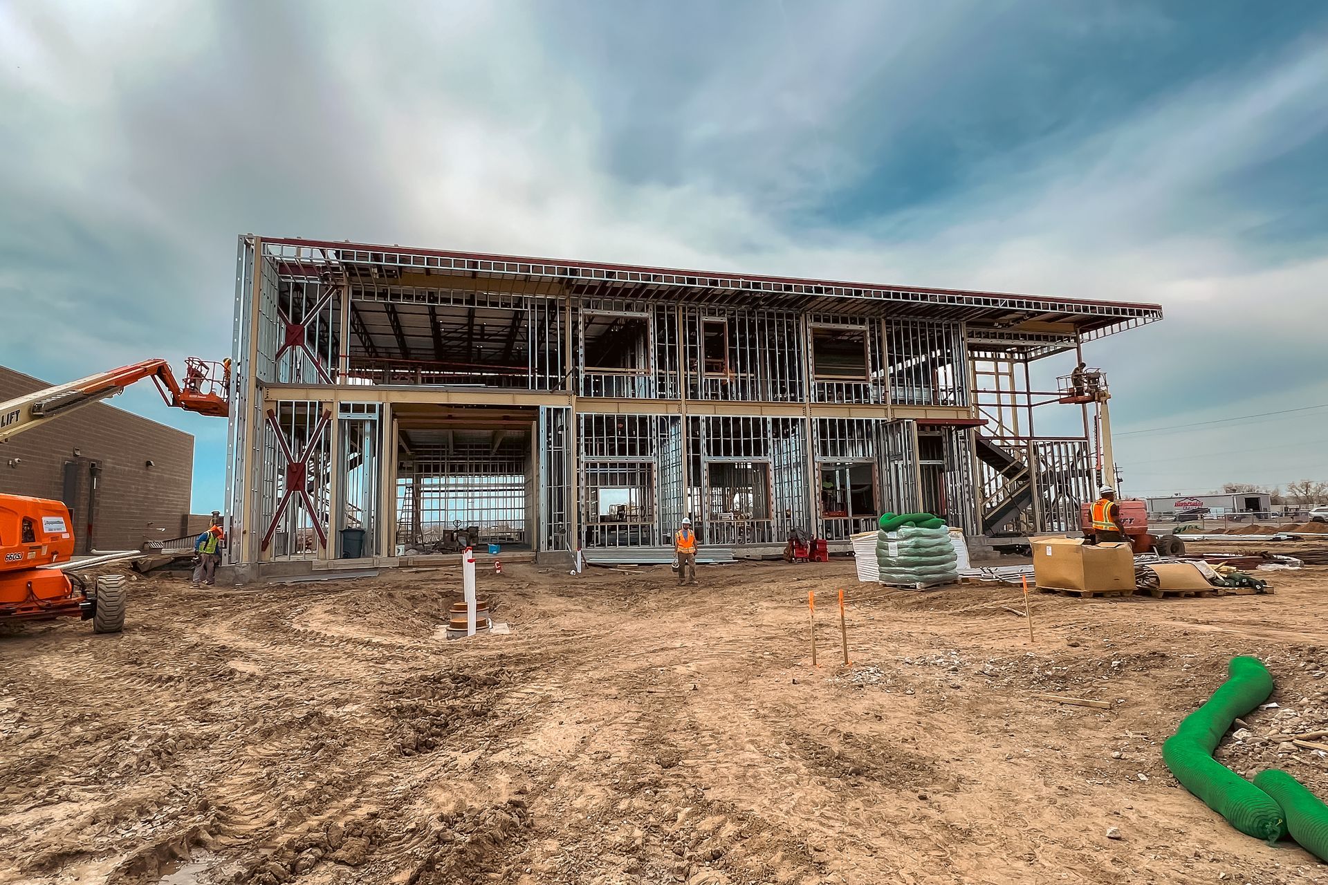 A large building is being built in the middle of a dirt field.
