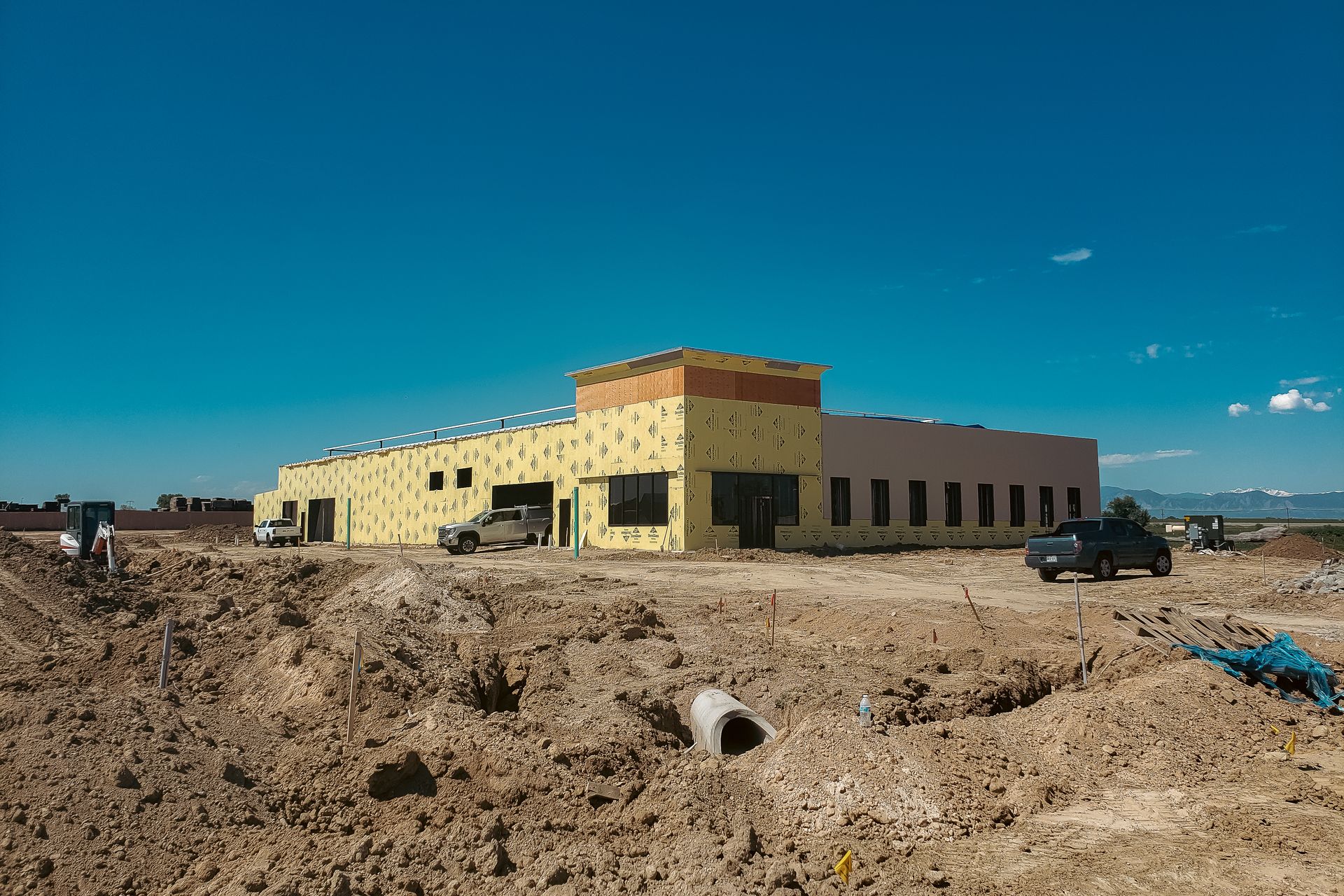 A large building is being built in the middle of a dirt field.