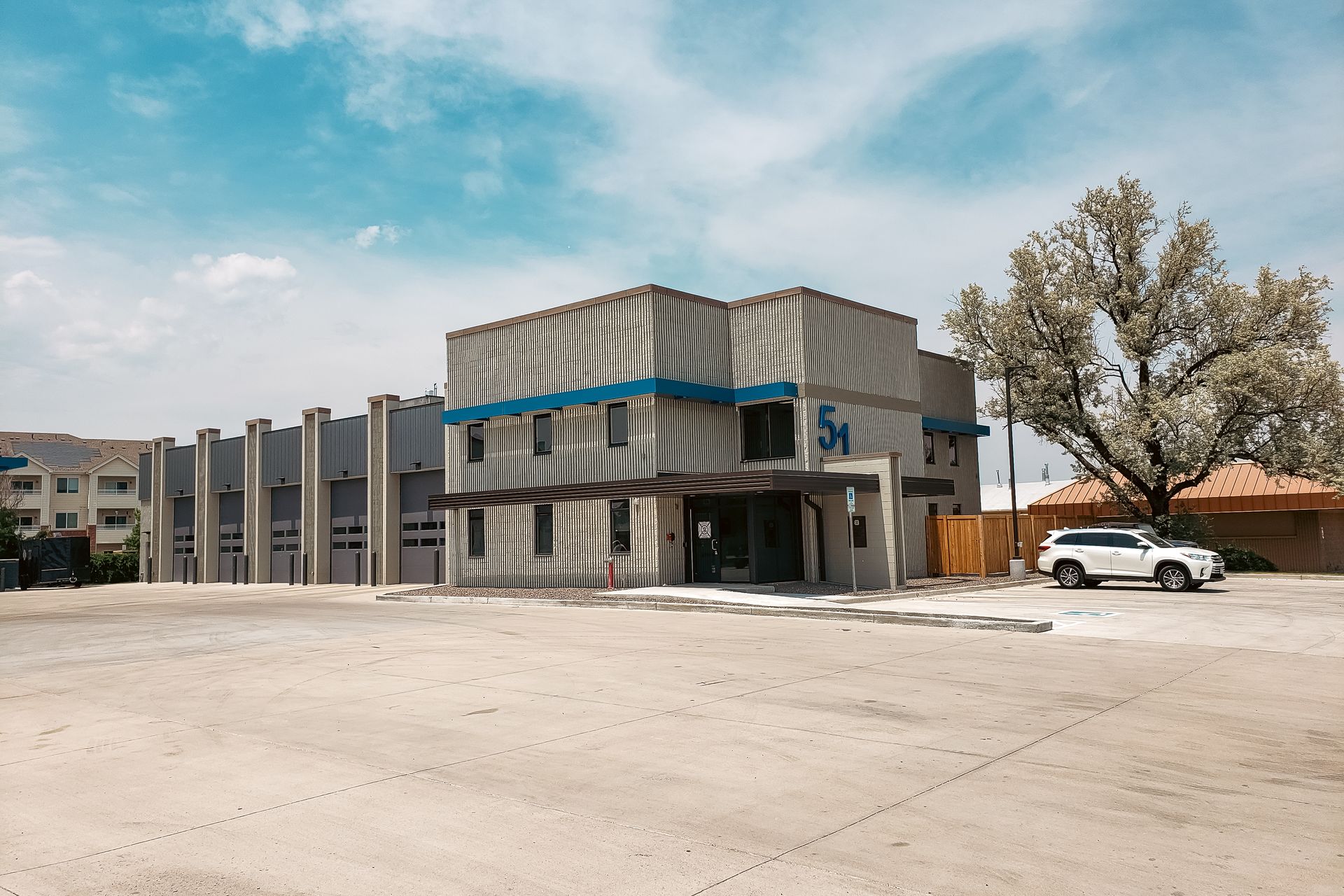 A white suv is parked in front of a large building.