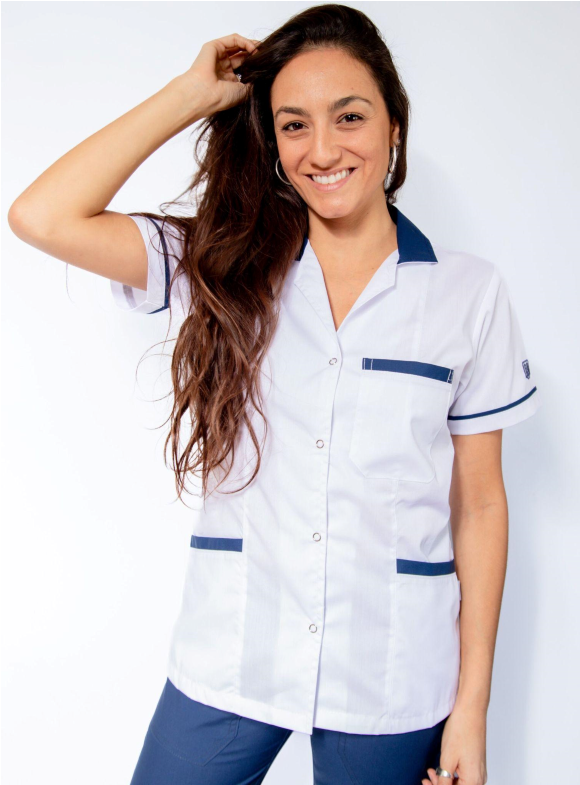 Una mujer que lleva una camisa blanca y pantalones azules está sonriendo.