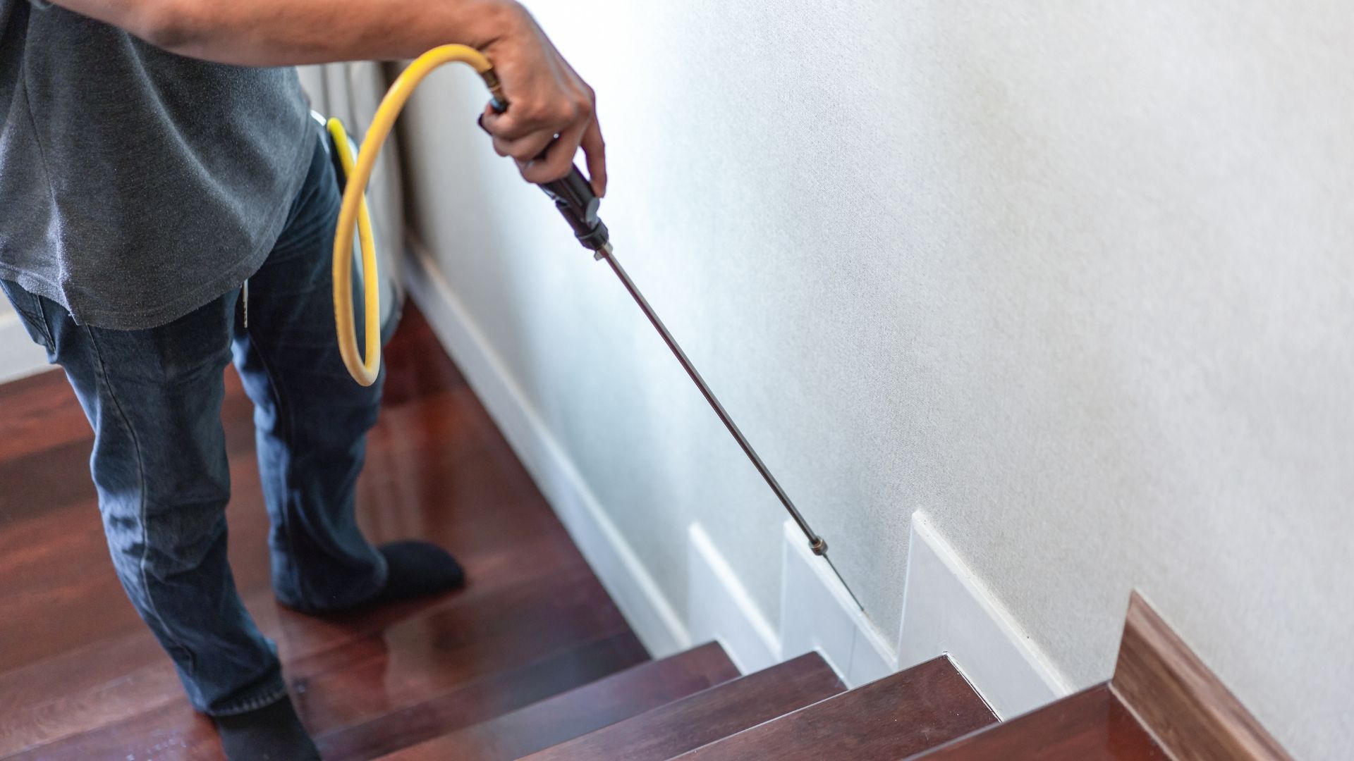 A man is spraying a wall with a hose on a set of stairs.