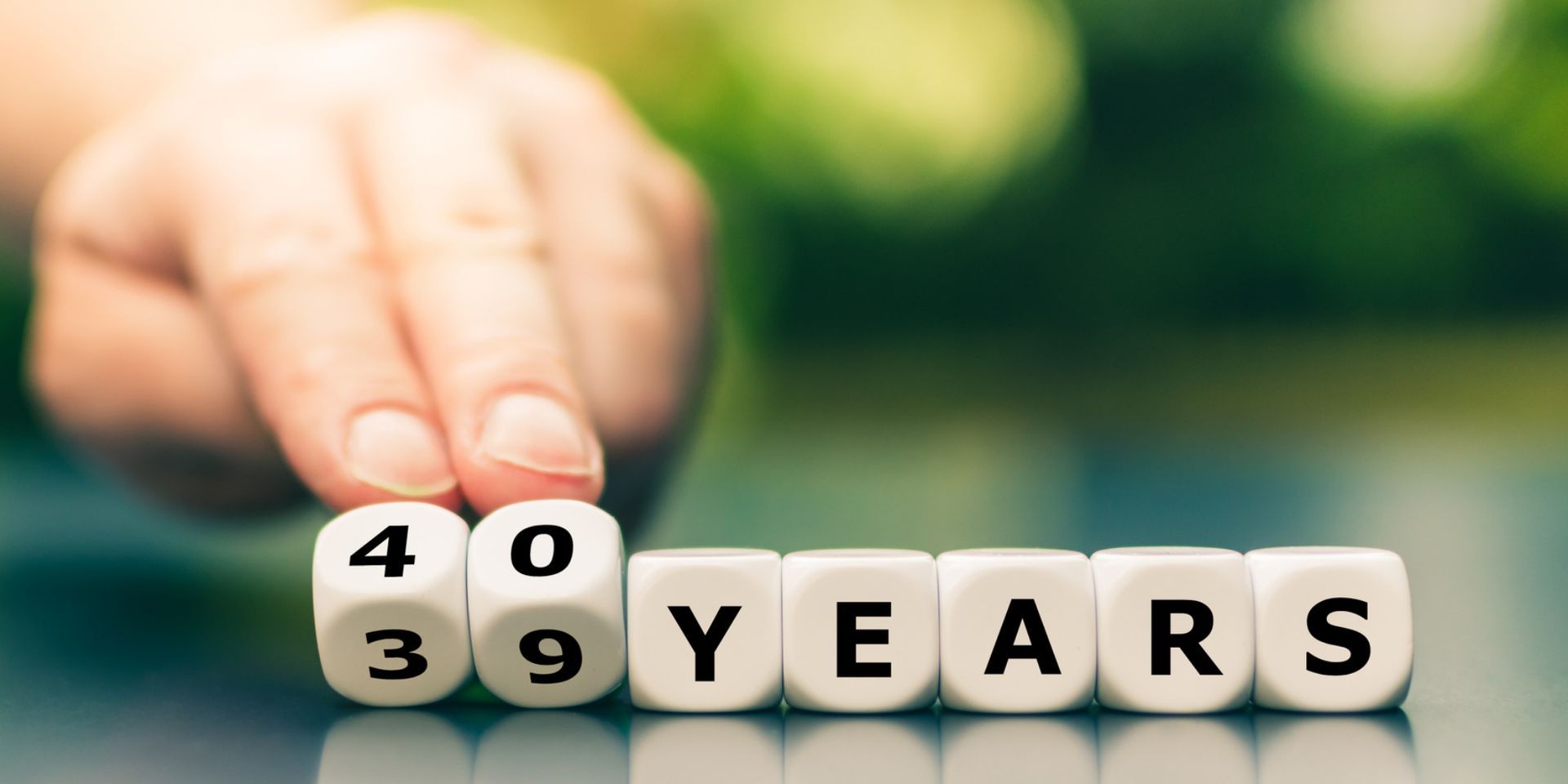 A person is holding dice that spell out the word 40 years.