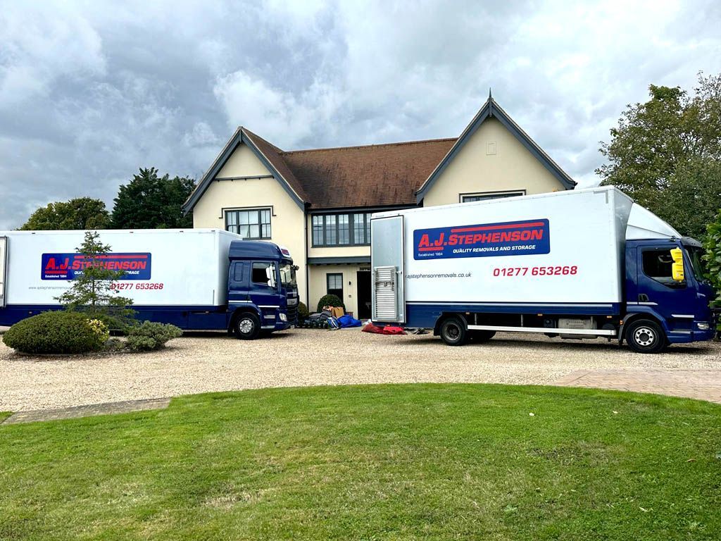 Two moving trucks parked in front of a house. 