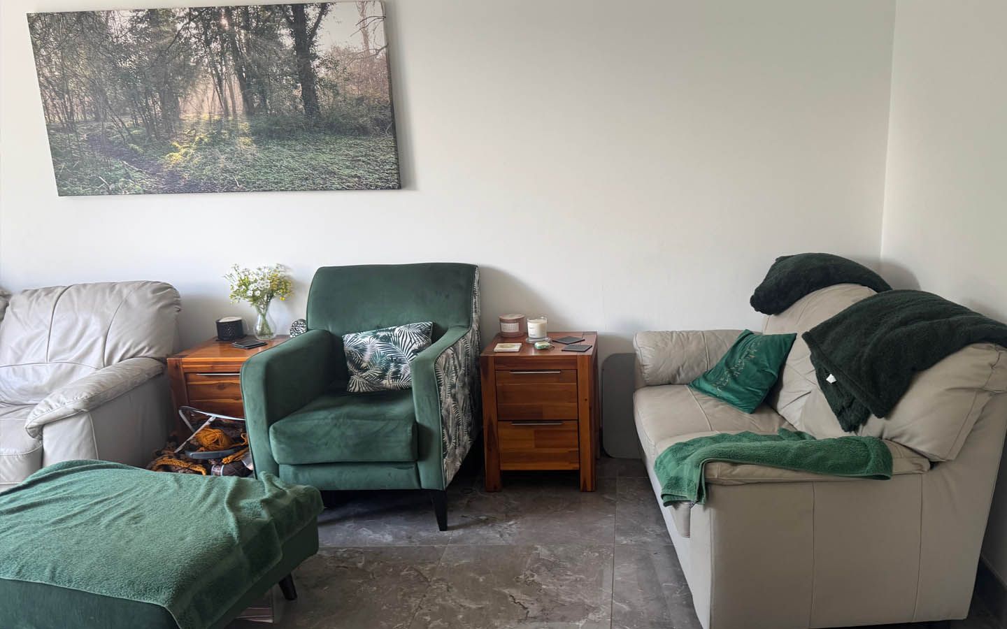 Living room with green and beige furniture, a painting on the wall, and a small wooden table.