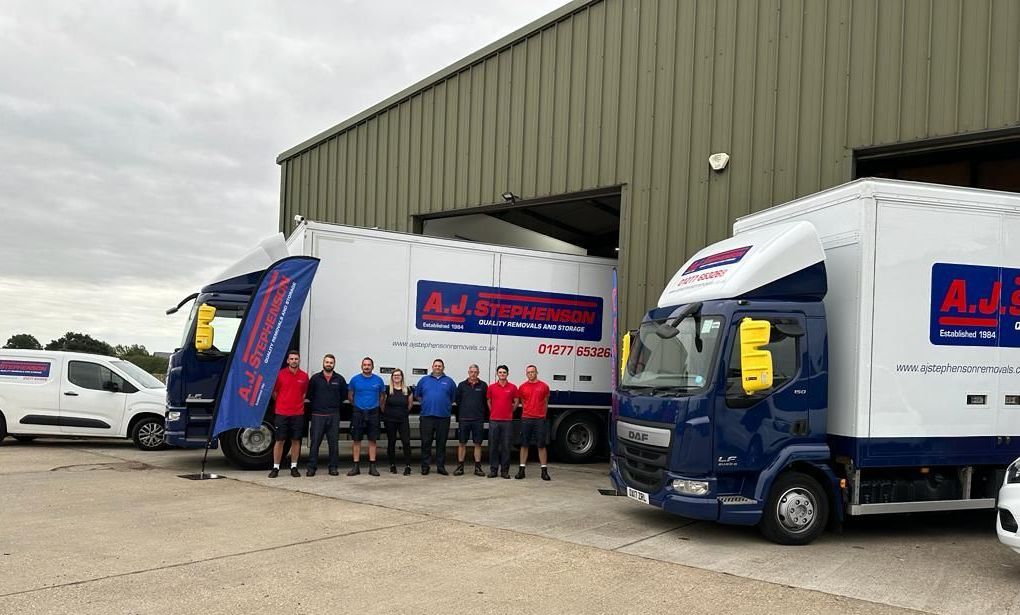 AJ Stephenson Removals team standing in front of a row of their removal lorries.