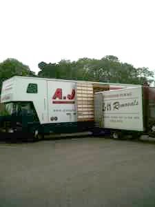 Two moving trucks are parked next to each other on the side of the road.