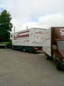 Two moving trucks are parked next to each other in a parking lot.