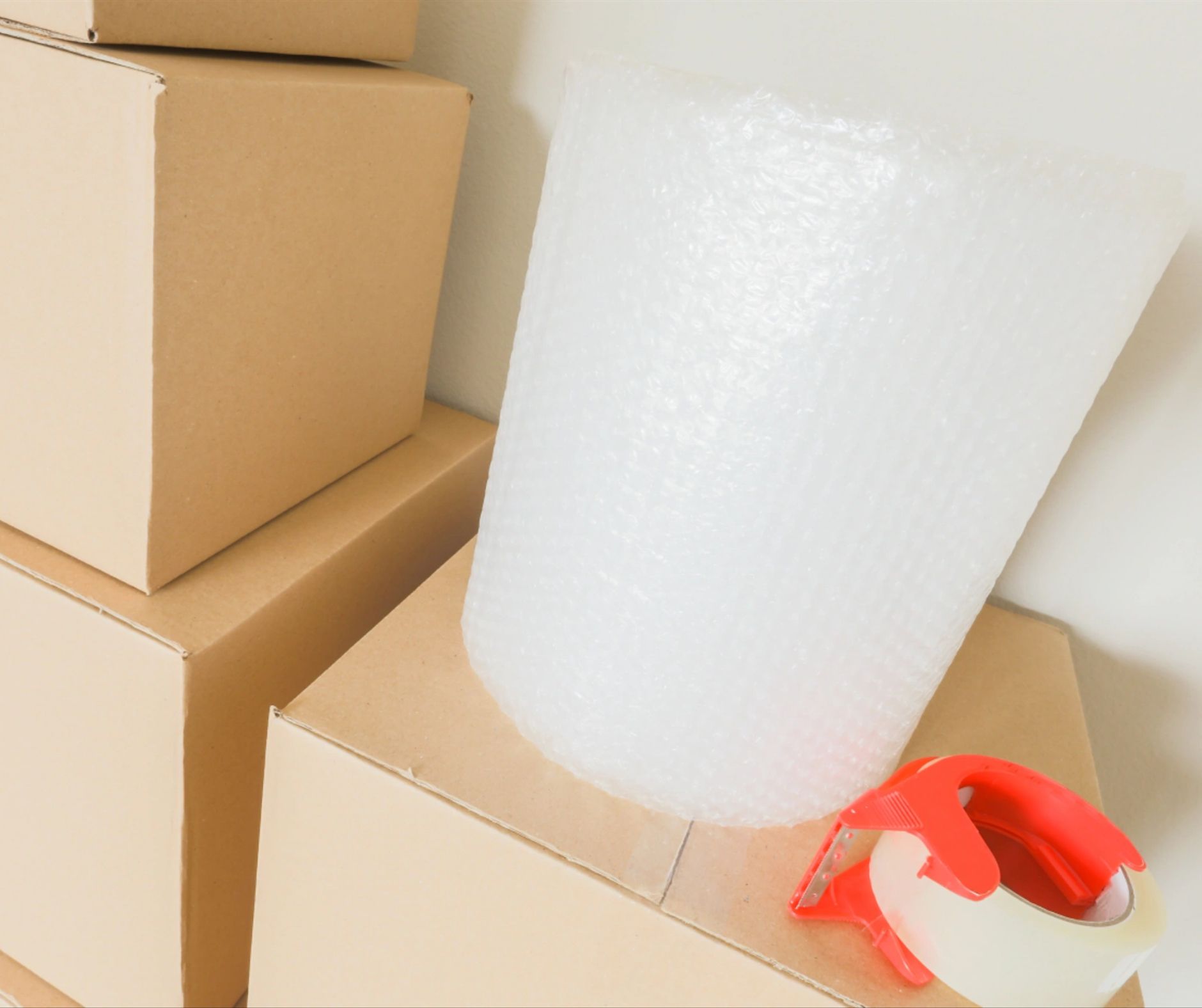 Cardboard moving boxes, bubble wrap, and tape dispenser.