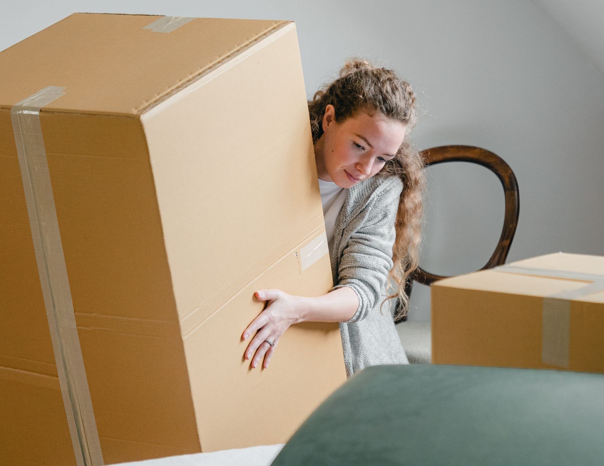 A woman is peeking out from behind a cardboard box