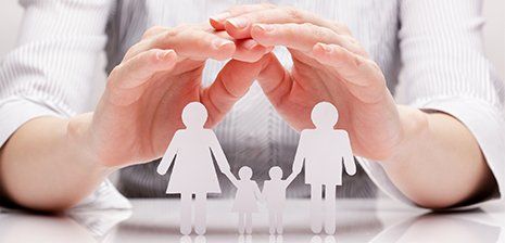 Family Law — Closeup of Hands Cupping Over White Paper Cutout of a Family in Laredo, TX