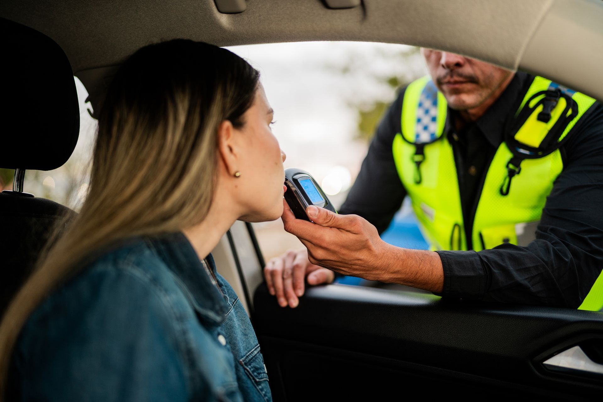A young woman in her car is doing a driver alcohol test with a police officer. A young woman in her car is doing a driver alcohol test with a police officer.