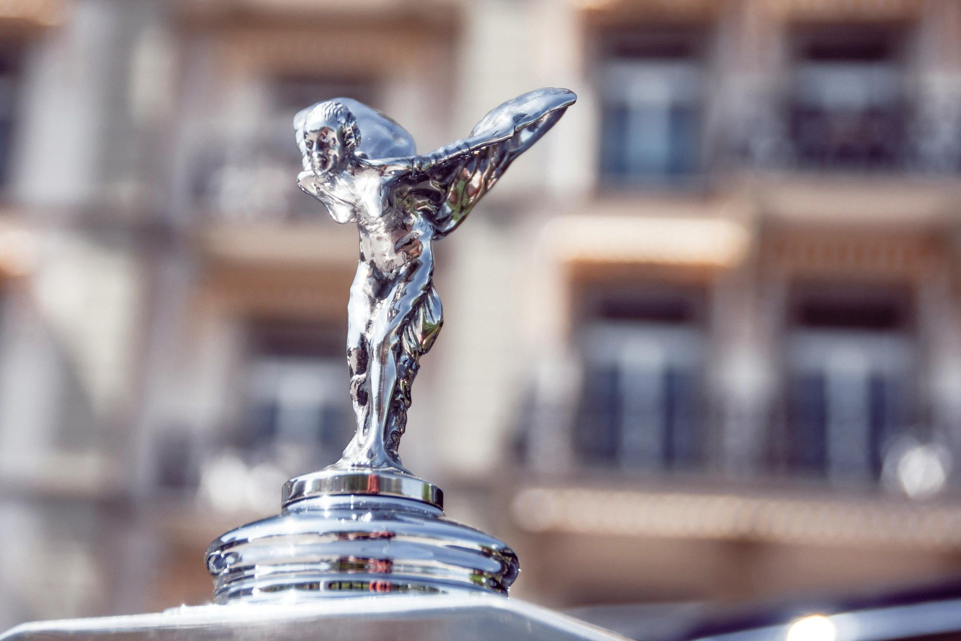 A statue of a woman with wings is on the hood of a car.