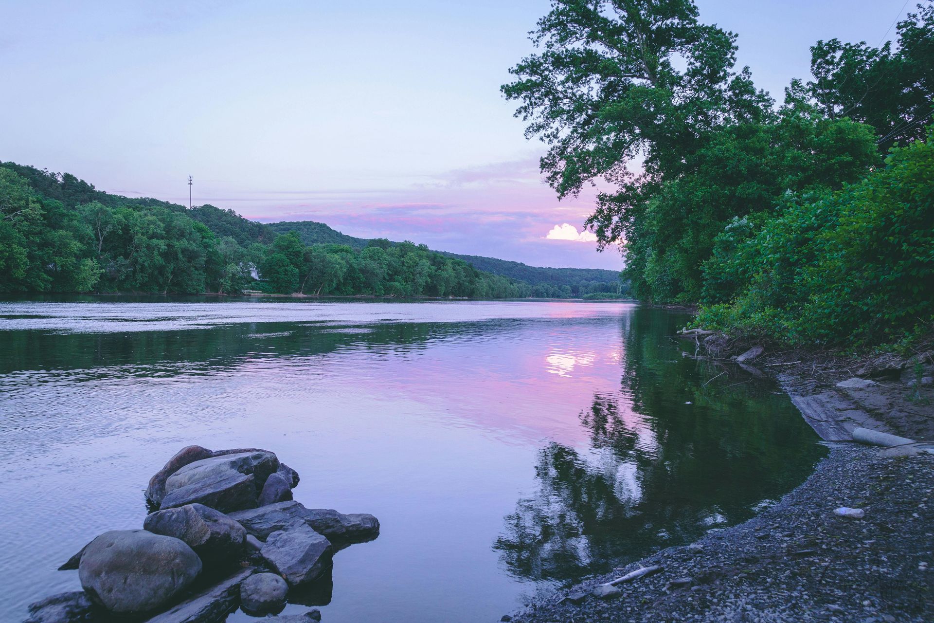 river falls wi A large body of water surrounded by trees and rocks at sunset.