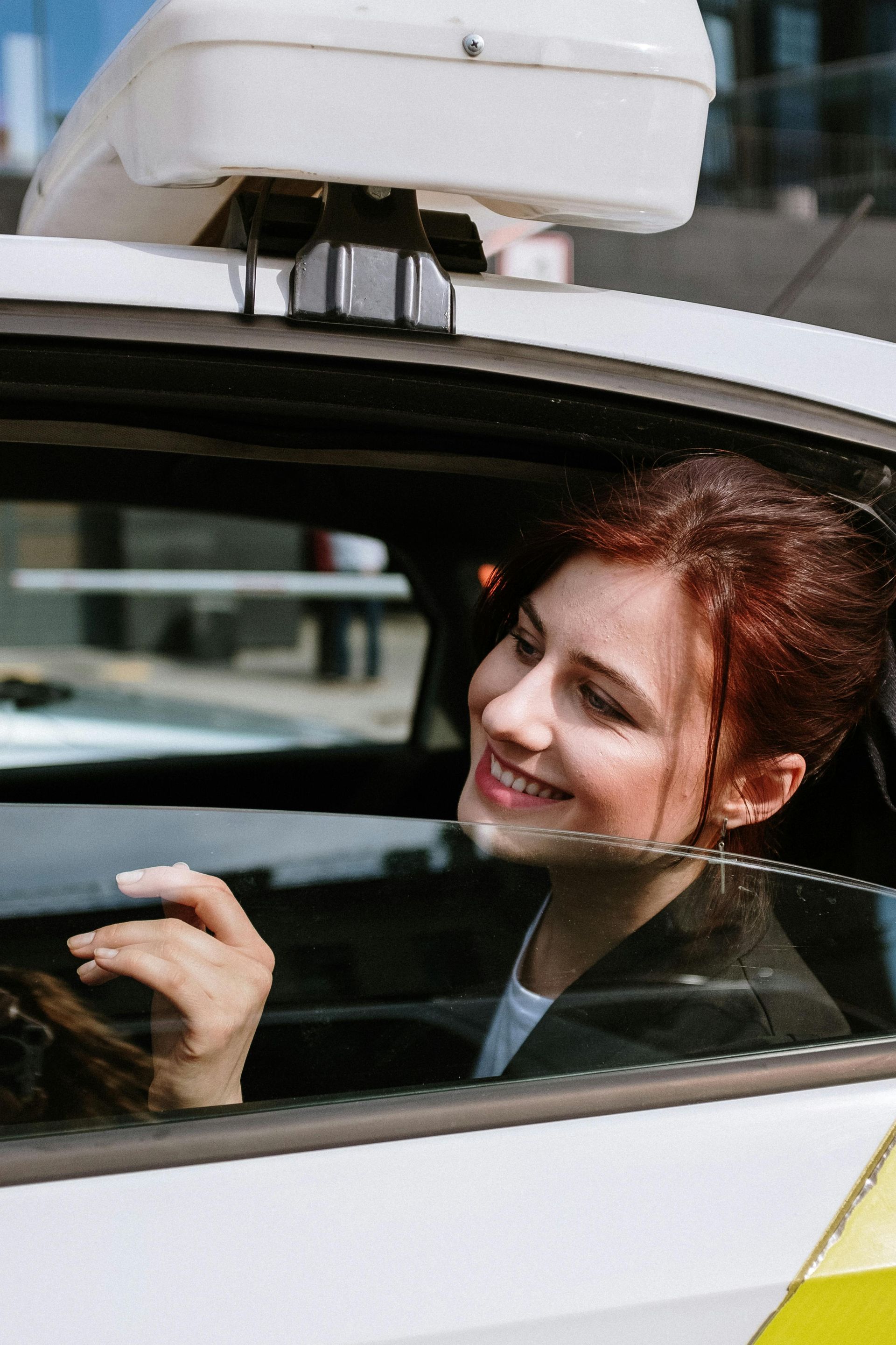 A woman is sitting in the driver 's seat of a car and smiling.