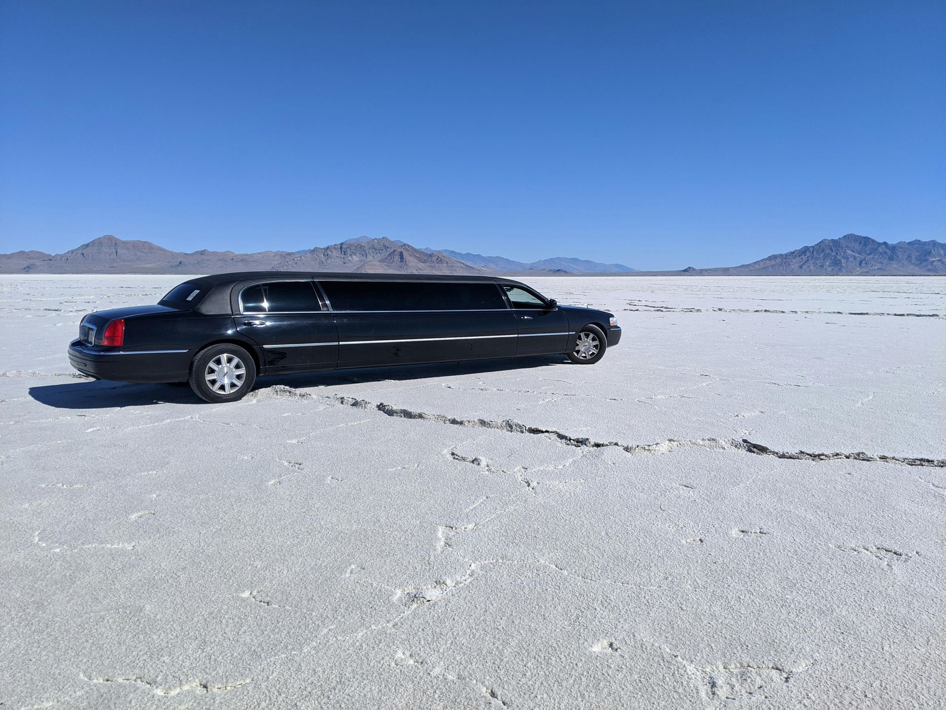 A black limousine is parked in the middle of a desert