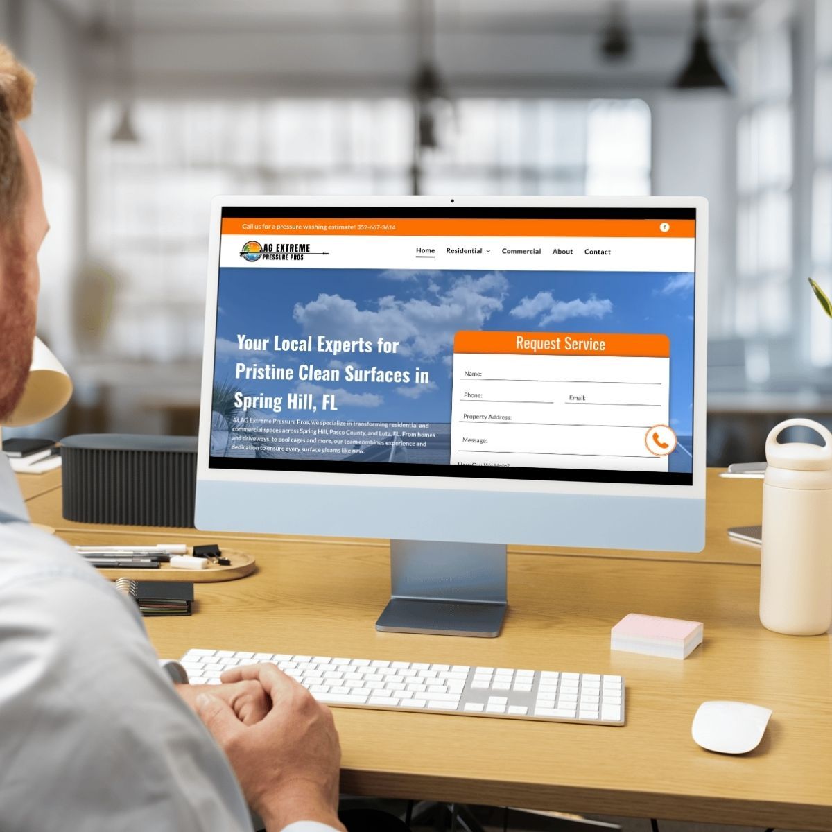 A person at a desk looks at a computer screen displaying a website.