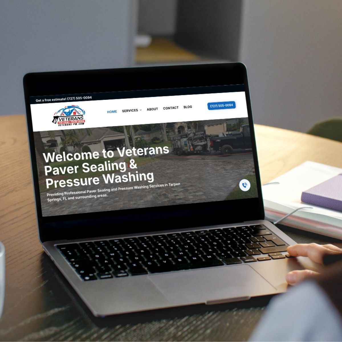 Person using a laptop displaying the website of Veterans Paver Sealing & Pressure Washing.