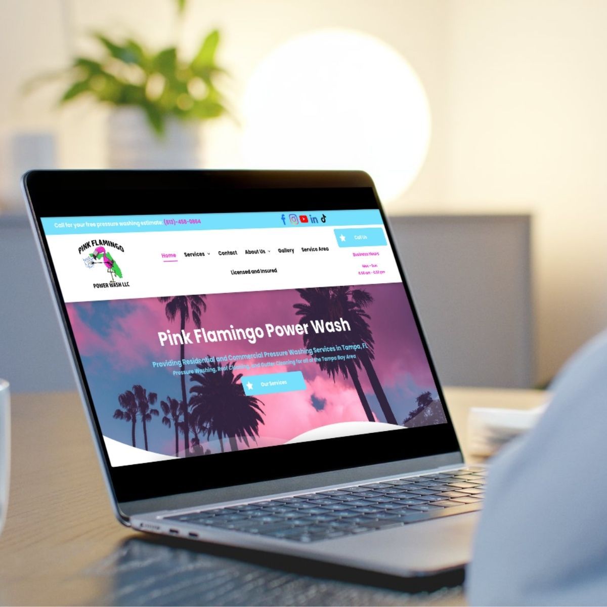 Laptop screen displaying the Pink Flamingo Power Wash website. The website features a pink and blue sunset with palm trees.
