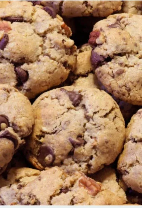a close up of a pile of chocolate chip cookies with pecans and chocolate chips .