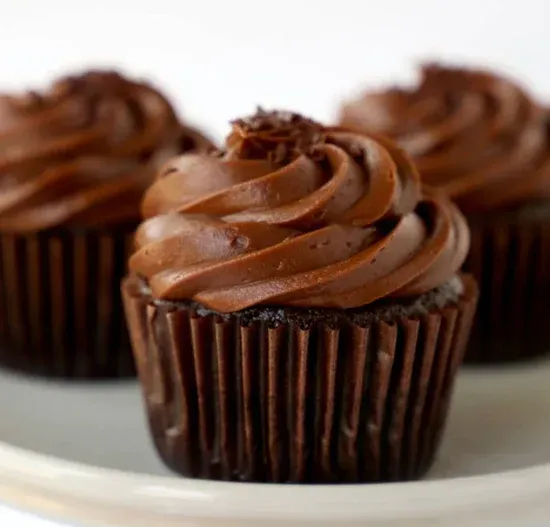 a close up of a chocolate cupcake with chocolate frosting on a plate .