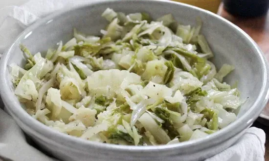 a close up of a bowl of cabbage and onions on a table .
