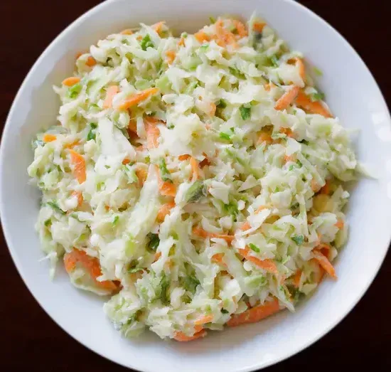 a white bowl filled with coleslaw and carrots on a table .
