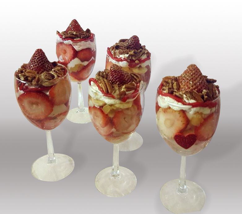 four wine glasses filled with strawberries pecans and whipped cream