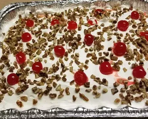a casserole dish filled with whipped cream , cherries and walnuts .