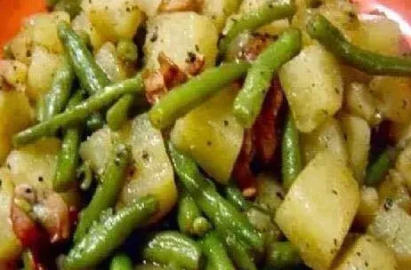 a close up of a plate of green beans and potatoes .
