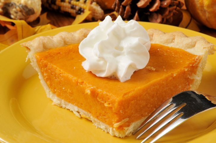 a slice of sweet potato pie with whipped cream on top on a yellow plate