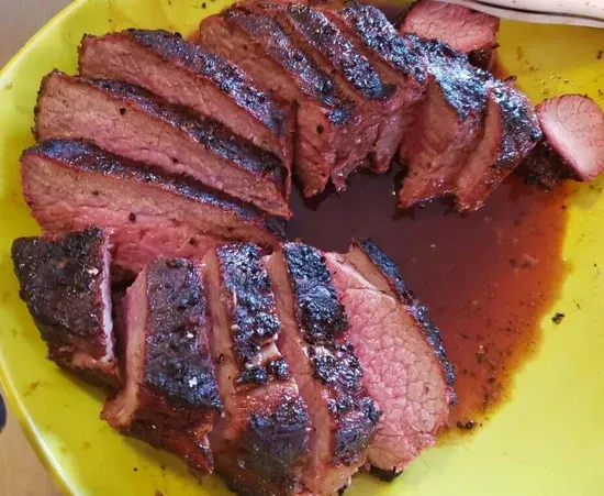 a yellow plate topped with sliced beef and sauce .