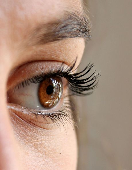 A close up of a woman 's brown eye with long eyelashes.