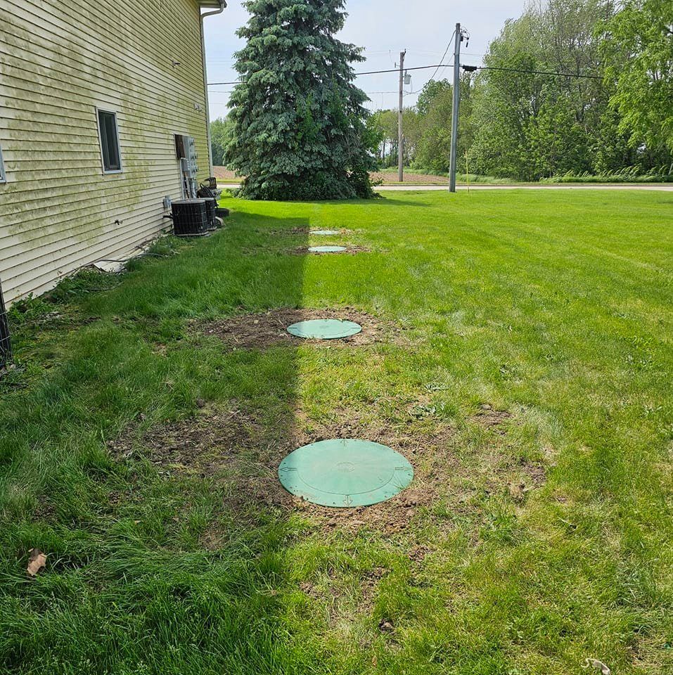 There are two green circles in the grass in front of a house.
