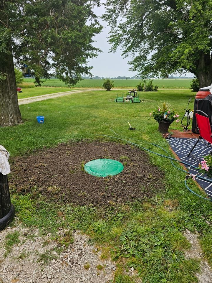A green septic tank is sitting in the middle of a lush green field.